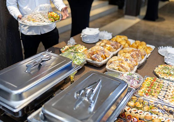 Guests are presented with an array of delectable foods on a long table during a formal event. The enticing assortment includes pastries, appetizers, and colorful salads.