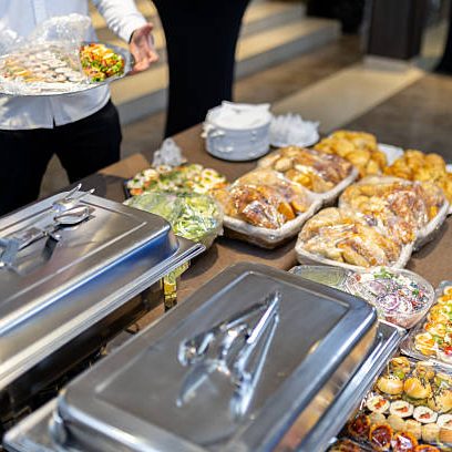 Guests are presented with an array of delectable foods on a long table during a formal event. The enticing assortment includes pastries, appetizers, and colorful salads.